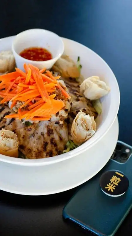 Platter of pan fried dumplings with shredded carrots and dipping sauce