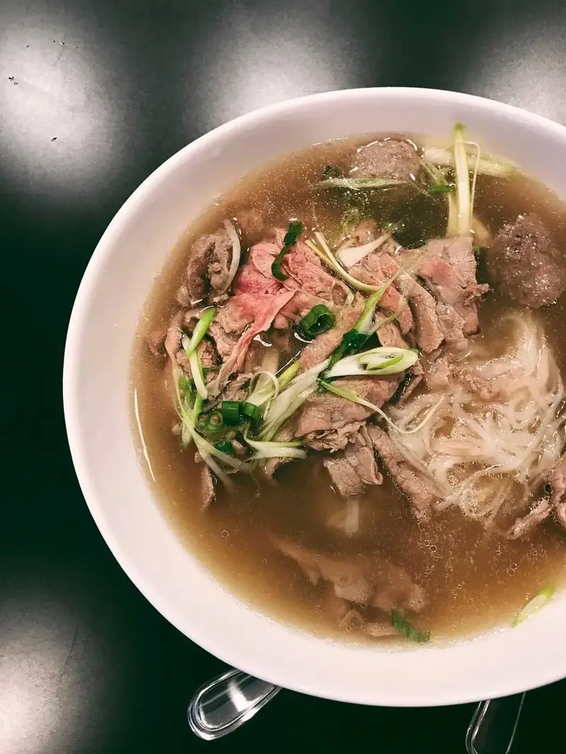 Bowl of pho with sliced beef, rice noodles and herbs