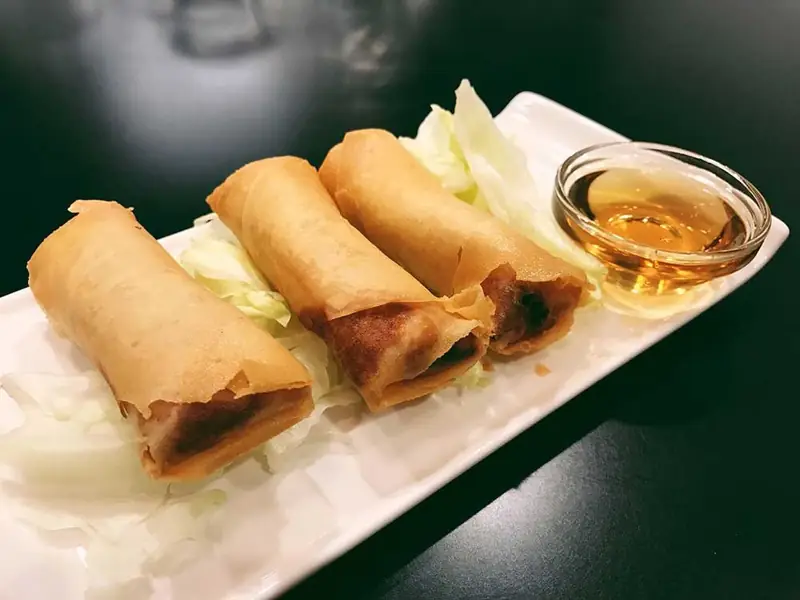 Three golden fried spring rolls with dipping sauce