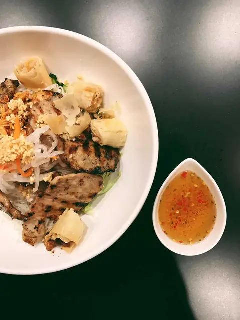 Vermicelli bowl with grilled meat, a spring roll and a side of nuoc cham